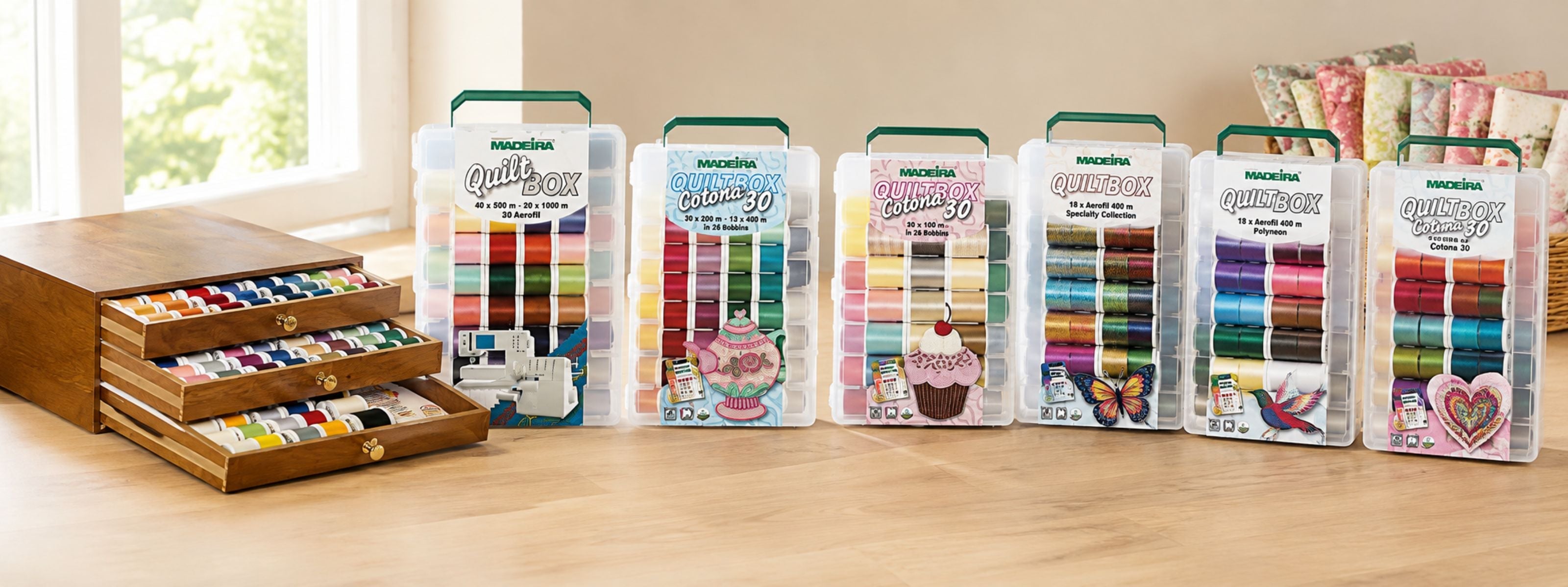 Madeira Quilting Thread assortment collection with a wooden thread chest and multiple colorful Quilt Box thread kits displayed in a bright sewing room.
