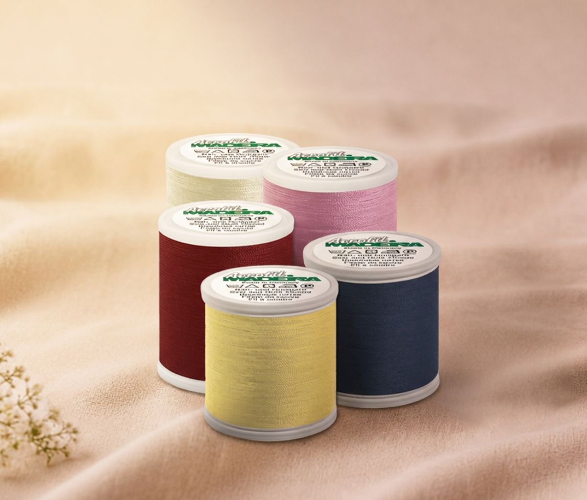 Madeira Aerofil all-purpose sewing thread spools in assorted colors displayed on soft fabric for sewing, quilting, and everyday stitching projects.