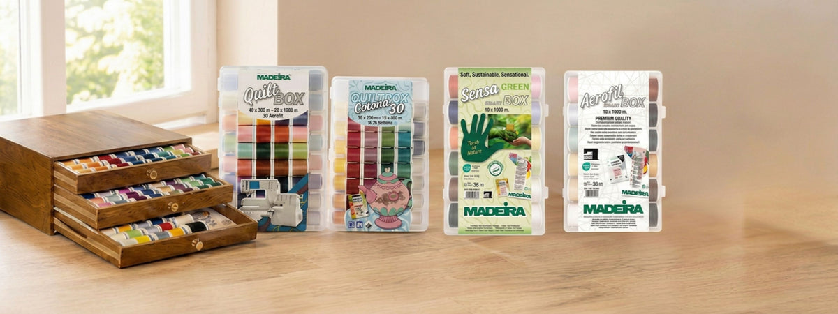 Madeira Quilting Thread assortment collection featuring a wooden thread chest, Quilt Box, Cotona 30, Sensa Green, and Aerofil thread assortments displayed on a sewing-room table.