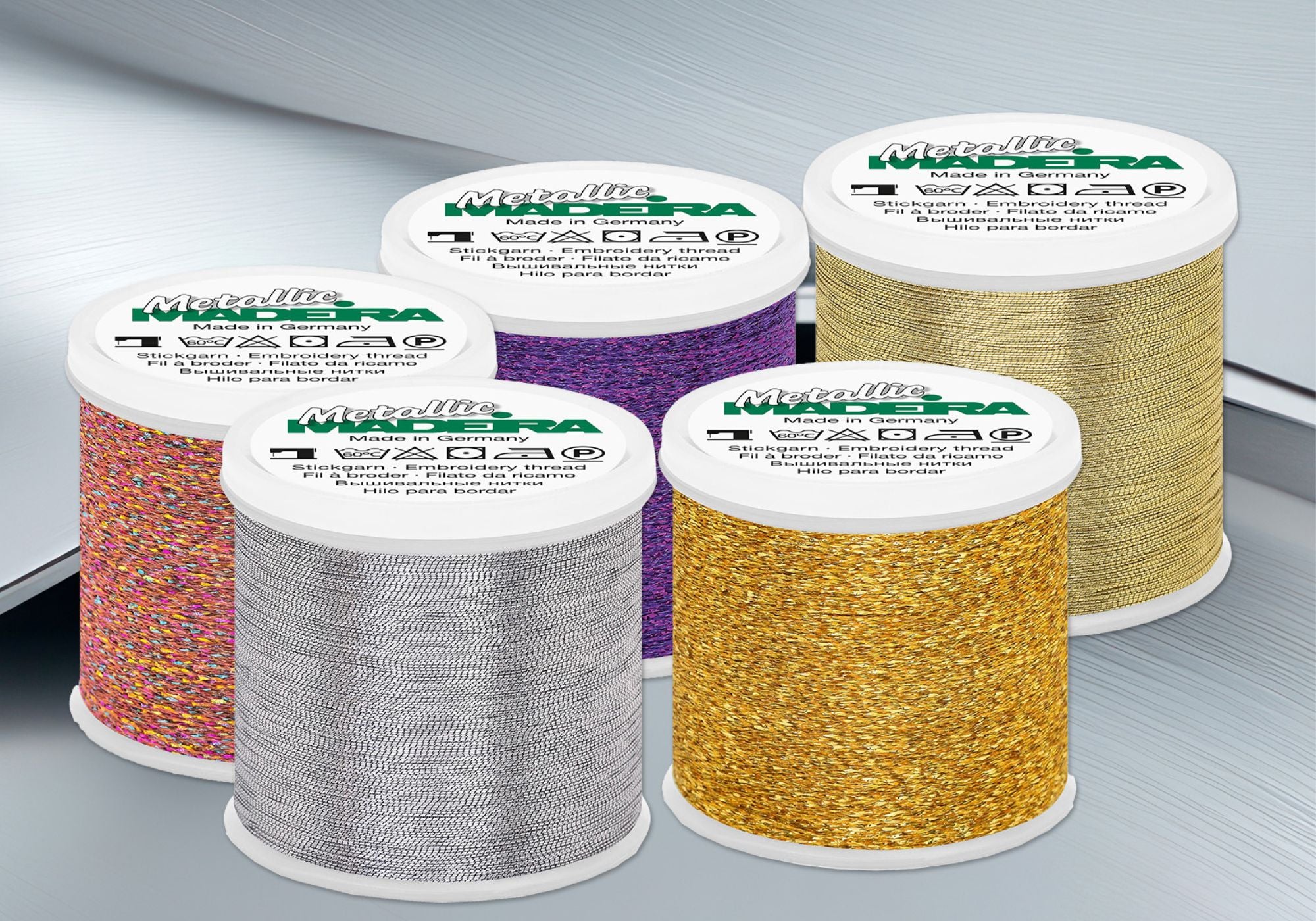 Madeira Metallic embroidery thread cones in gold, silver, rainbow, and specialty metallic colors, featuring high-shine decorative thread for machine embroidery and embellishment projects.