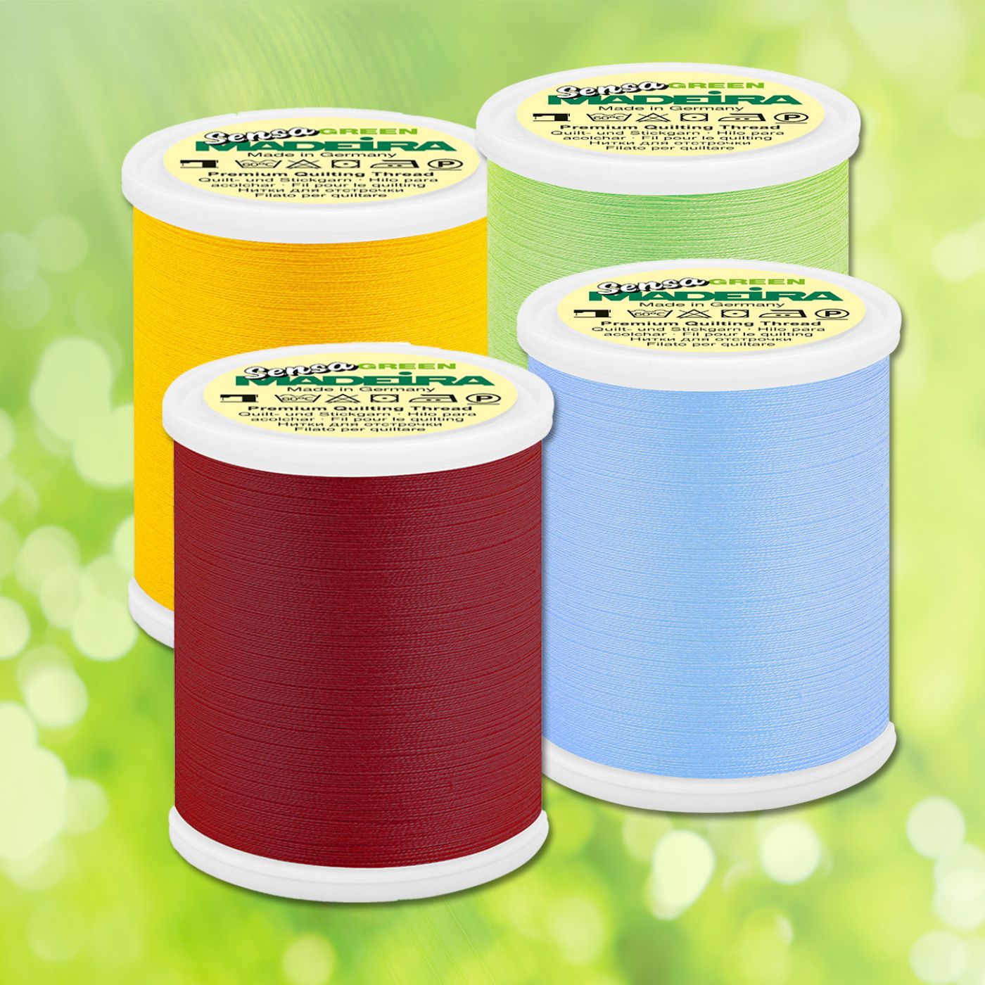 Four Madeira Sensa Green quilting thread spools in red, yellow, green, and light blue arranged on a soft green background.
